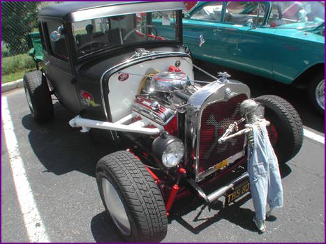 THAT FELLA IN FRONT OF THIS STREET ROD LOOKS LIKE HE MISSED BREAKFAST